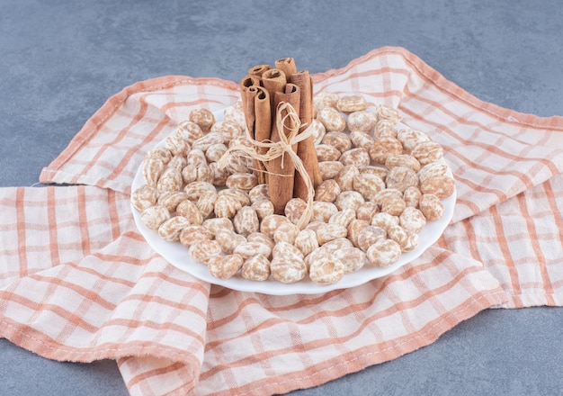 Pijpjes kaneel en koekjes op de handdoek, op de marmeren achtergrond.