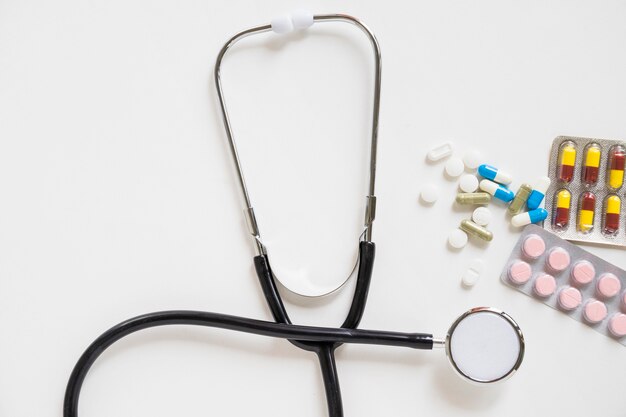 Pillen en geneeskundeblaar met stethoscoop over witte achtergrond