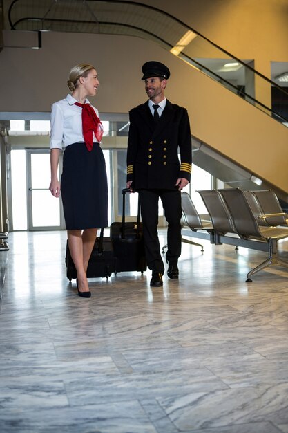 Piloot en stewardess lopen met hun trolleytassen