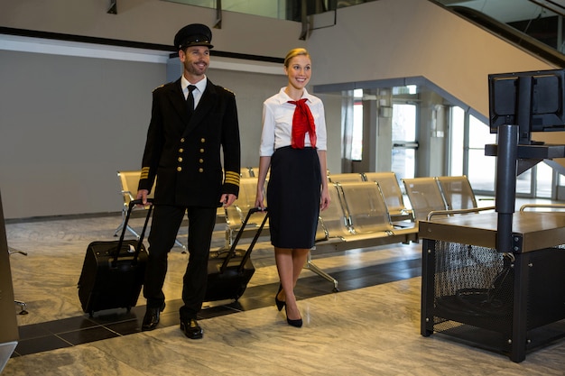 Piloot en stewardess lopen met hun trolleytassen