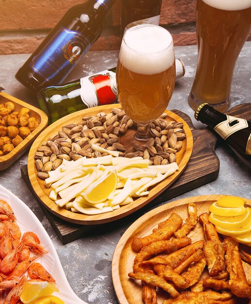 Pils en snacks op houten tafel. Noten, kaaschips, pistachenoten, crevettes