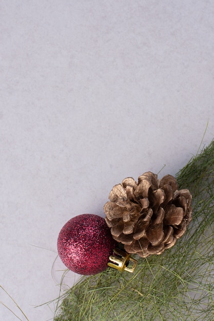 Pinecone met kerstbal op witte ondergrond