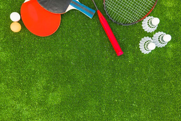 Pingpongballen; shuttles; badminton en rackets op groene grasmatten