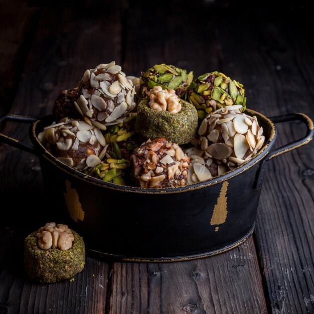 Pistachekoekjes in een zwarte pot op een donkere houten achtergrond. hoge hoekmening.