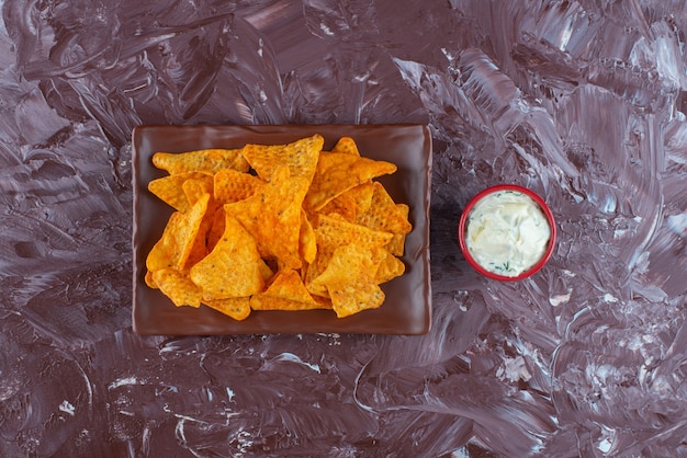 Pittige chips op een bord naast een kom mayonaise, op de marmeren tafel.