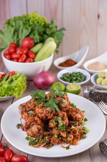 Pittige kipgehakt op een wit bord compleet met komkommer, sla en bijgerechten.
