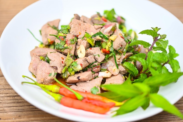 Pittige leversalade op witte plaat houten tafel achtergrond varkensleversalade met verse chili kruiden specerijen thais eten Premium Foto