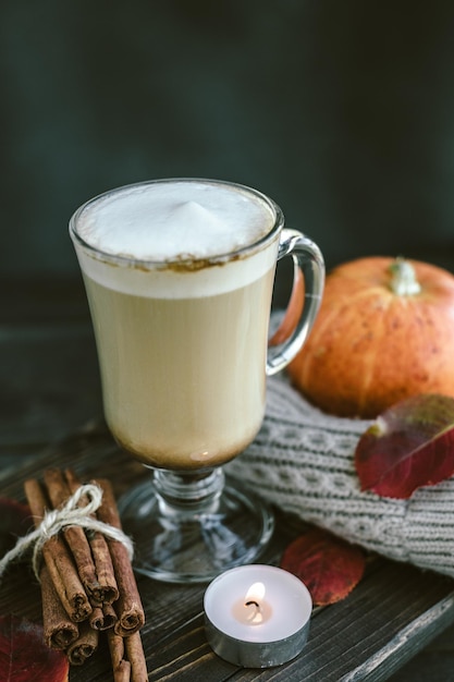 Pittige pompoen latte op een houten bord met een trui