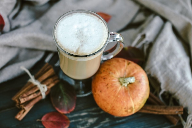 Pittige pompoen latte op een houten bord met een trui