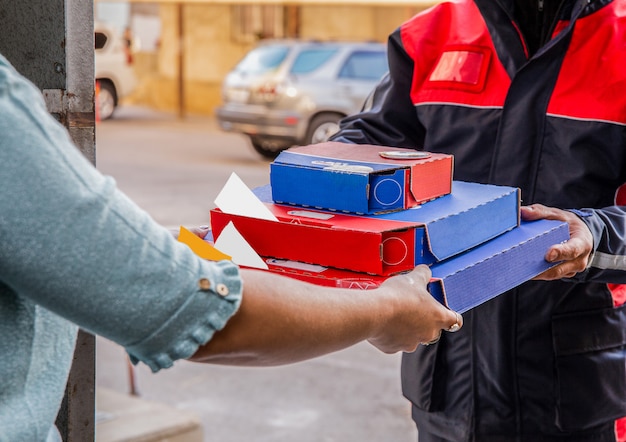 Gratis foto pizza bezorging. een koerier die pizzadozen aan een persoon geeft.