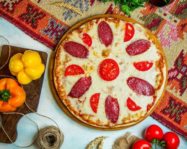 Pizza gegarneerd met worstjes en tomaat