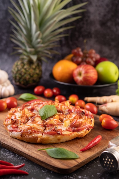 Pizza in een houten bakje met tomaten chili en basilicum.