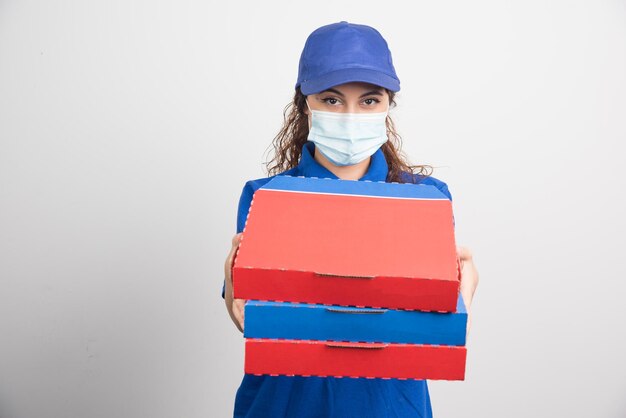 Pizzabezorger met drie dozen met medisch gezichtsmasker op wit