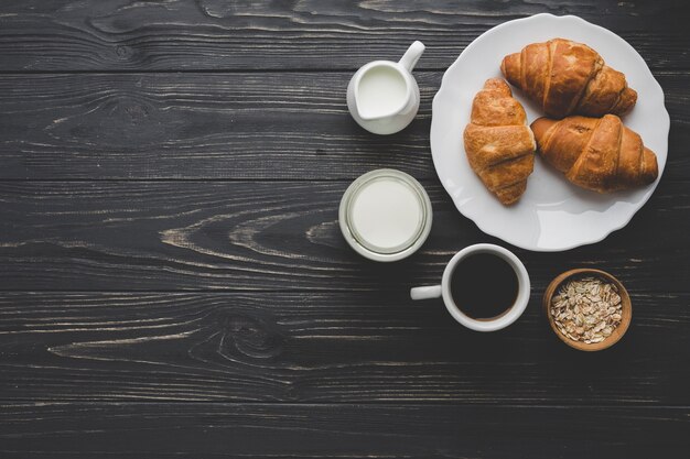 Plaat met croissants in de buurt van koffie en zuivelproducten