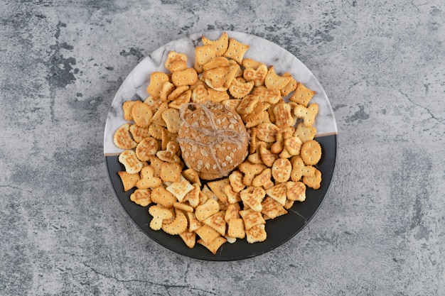 Plaat met gezouten crackers en havermoutkoekjes op marmeren achtergrond.