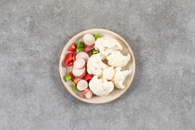 Plaat van gesneden verse groentesalade op steenoppervlak.