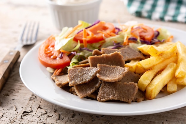 Plaat van kebab, groenten en frietjes op houten tafel