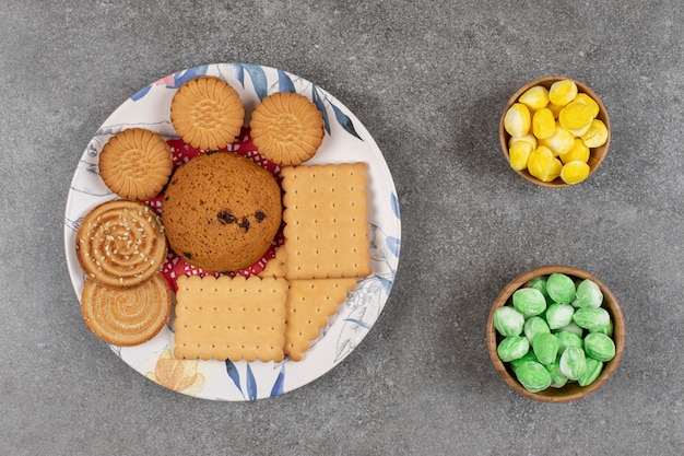 Plaat van knapperige koekjes en kleurrijk suikergoed op marmer.