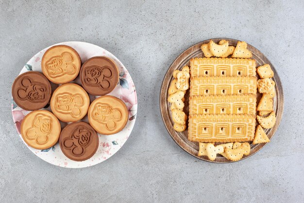 Plaat van scherpe koekjes naast een dienblad met gestapelde koekjes op marmeren achtergrond. Hoge kwaliteit foto