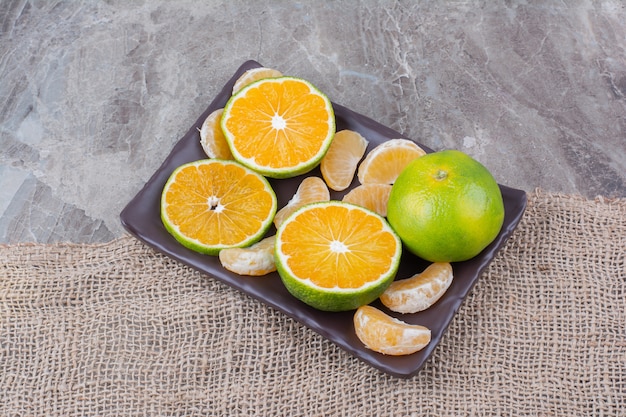 Gratis foto plaat van verse mandarijnen op stenen achtergrond.