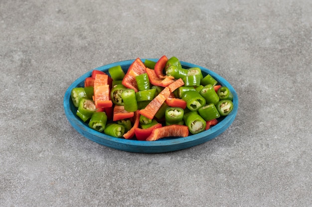 Plaat van verse salade met chili en paprika op marmeren oppervlak.