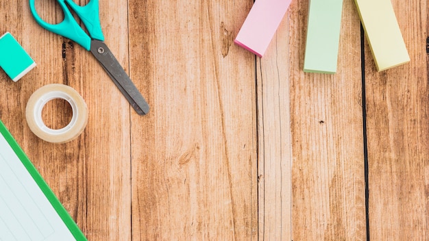 Plakbriefjes; schaar; tape en gum op houten tafel