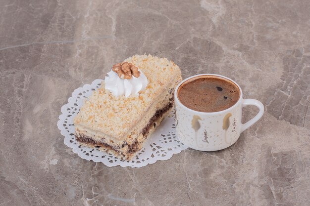 Plakje cake en kopje koffie op marmeren oppervlak.