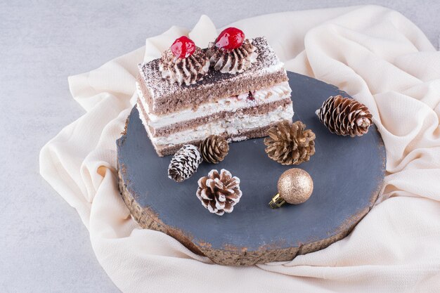 Plakje cake met Kerst ornamenten op houten stuk.