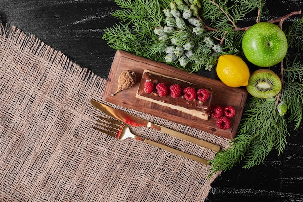 Plakje chocoladetaart op houten schotel.