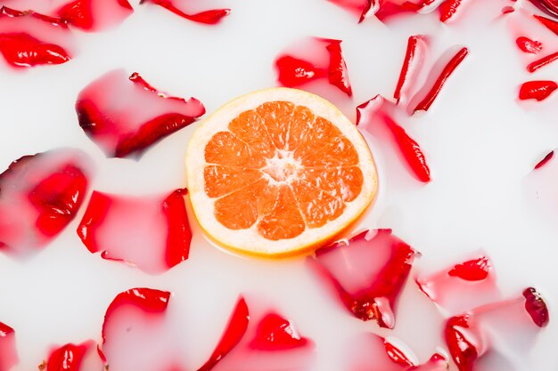 Plakje grapefruits en bloemblaadjes drijvend op helder wit water