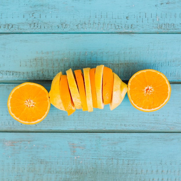 Gratis foto plakje sinaasappel en citroen fruit op blauwe houten achtergrond