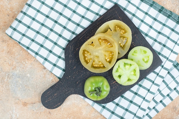 Plakjes ingemaakte tomaat en verse groene tomaten op donker bord