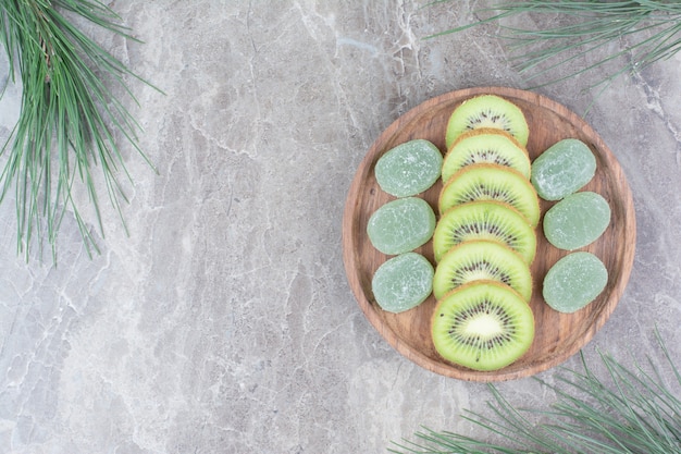 Gratis foto plakjes kiwi en marmelade op houten plaat.