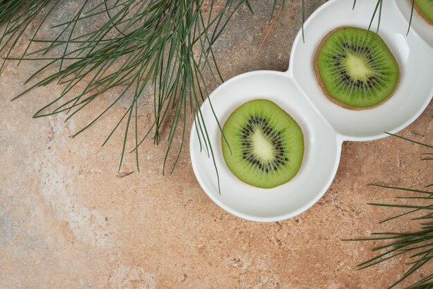 Plakjes verse kiwi op witte plaat.