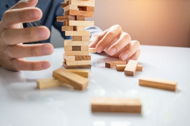 Gratis foto planning, risico en strategie in het bedrijfsleven, zakenman gokken plakken houten blok op een toren
