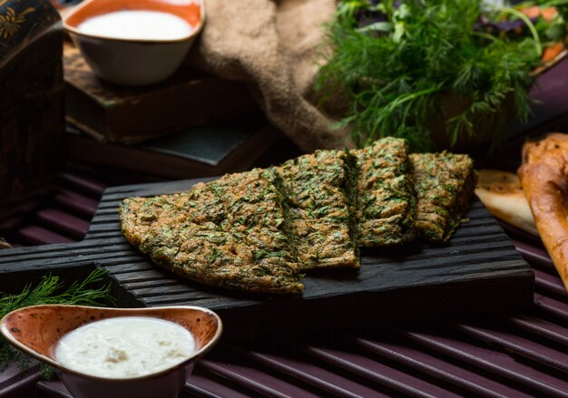 Plantaardige omlette, kuku, pizza gesneden en geserveerd op een stenen bord.