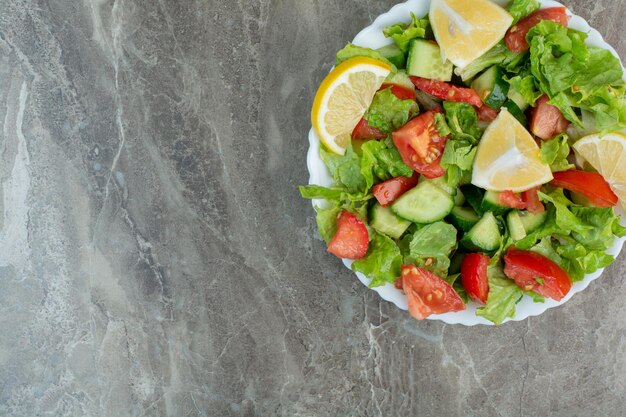 Plantaardige salade met schijfjes citroen op witte plaat. Hoge kwaliteit foto