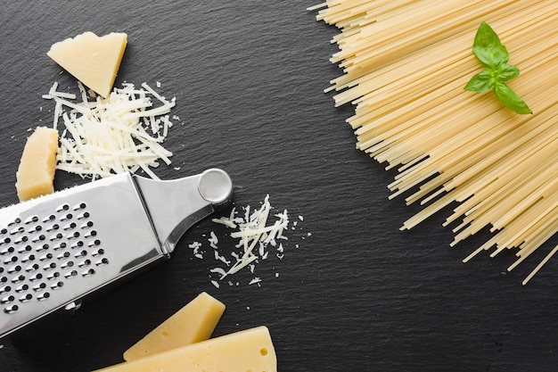 Plat geraspte Parmezaanse kaas en rasp met ongekookte spaghetti