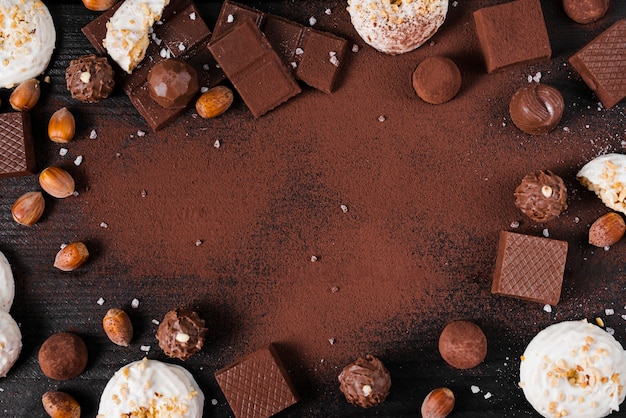 Gratis foto plat lag chocolade snoep mix en cacaopoeder op roze achtergrond met kopie ruimte