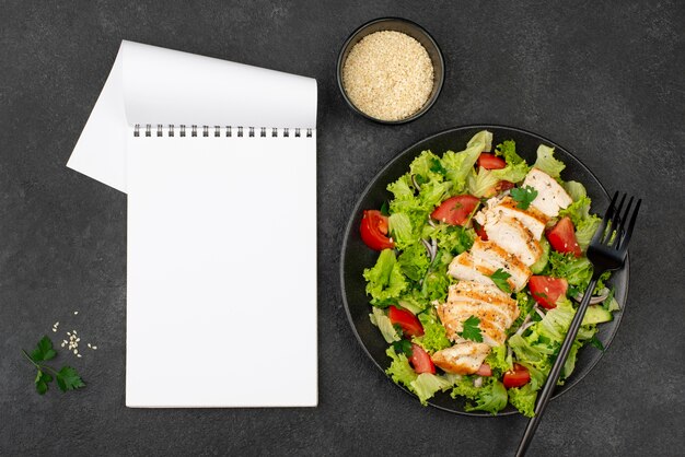 Plat lag salade met kip en sesamzaadjes met lege notebook