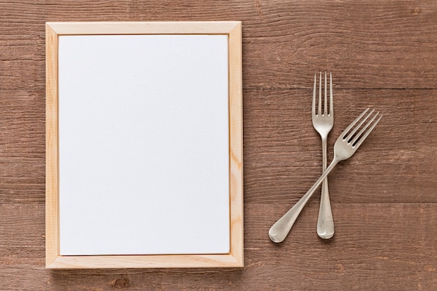 Gratis foto plat lag van blanco menu papier met bestek op houten oppervlak