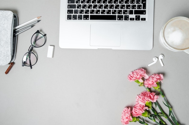 Plat lag vrouw bureau werkruimte met laptop roze anjer briefpapier op witte tafel Bovenaanzicht