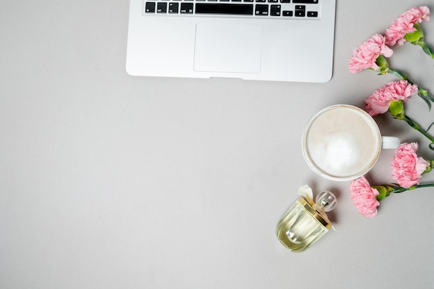 Plat lag vrouw bureau werkruimte met laptop roze anjer briefpapier op witte tafel Bovenaanzicht