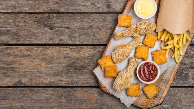 Gratis foto plat leggen van gebakken kip met sauzen en frietjes