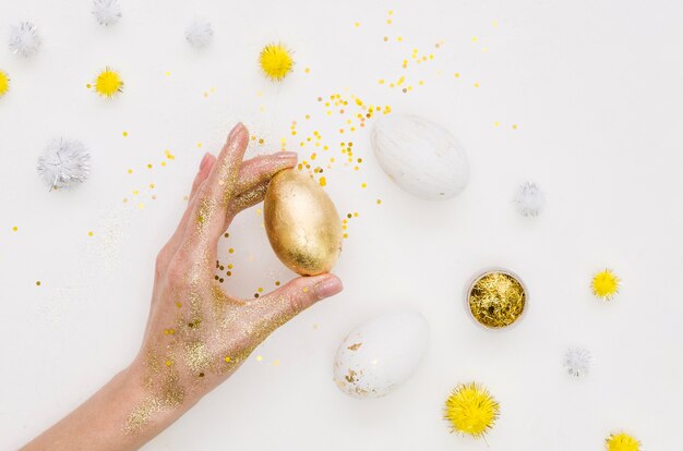 Plat leggen van hand houden bedrijf ei voor Pasen met paardebloemen en glitter