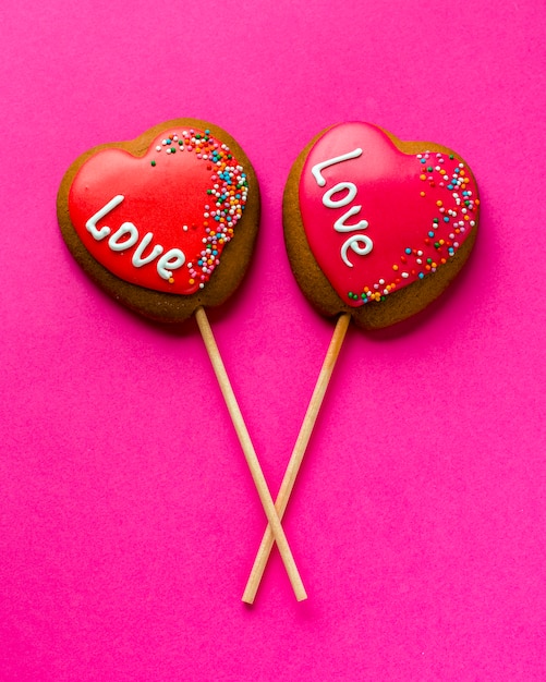 Plat leggen van hartvormige koekjes op stok en roze achtergrond
