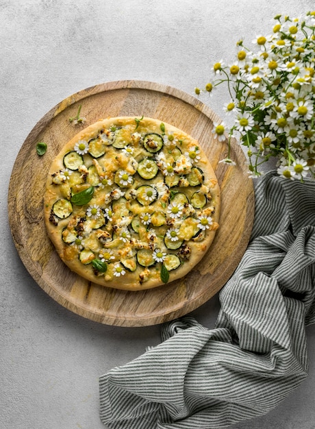 Gratis foto plat leggen van heerlijke gekookte pizza met een boeket van kamille bloemen