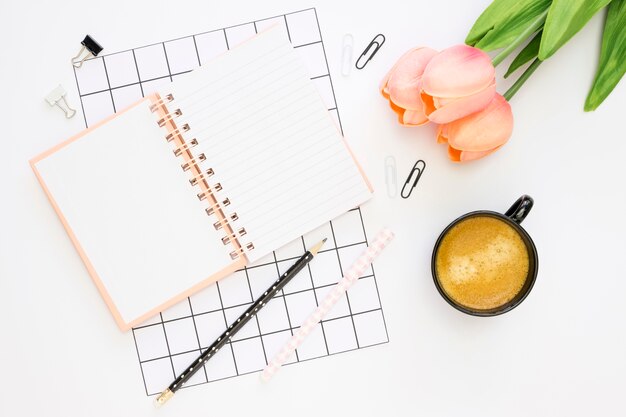 Plat leggen van kantoorbenodigdheden met tulpen en koffie