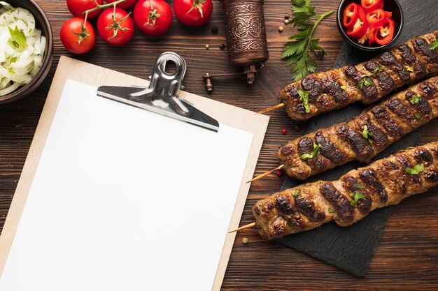 Plat leggen van Kladblok met heerlijke kebab en tomaten
