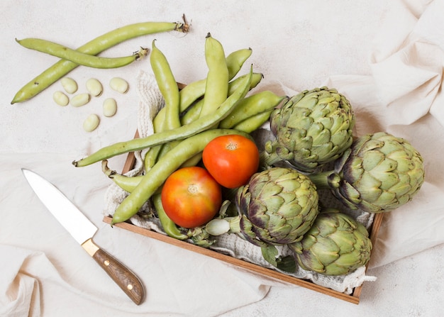 Gratis foto plat leggen van mand met artisjokken en tomaten